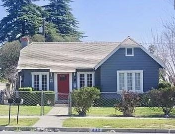 A blue house with a red door and white windows.