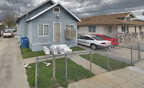 A blue house with a red car parked in front.