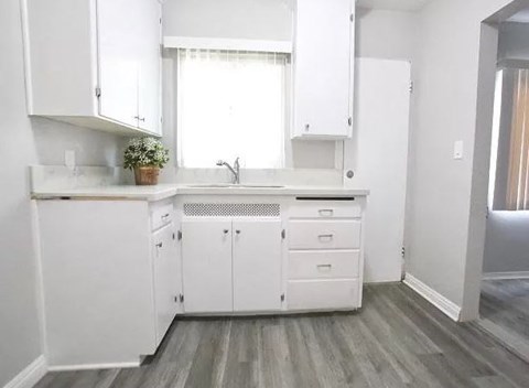 a white kitchen with white cabinets and a window
