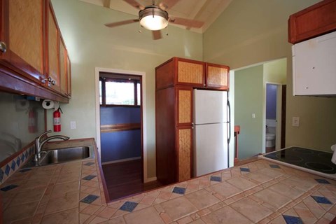 A kitchen with a refrigerator and a ceiling fan.