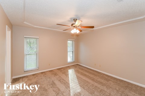 A spacious room with a fan and carpeted floor.