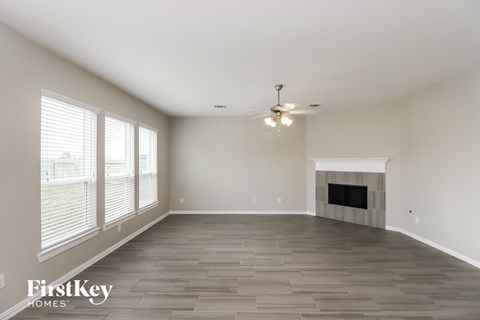 A spacious living room with a fireplace and a ceiling fan.