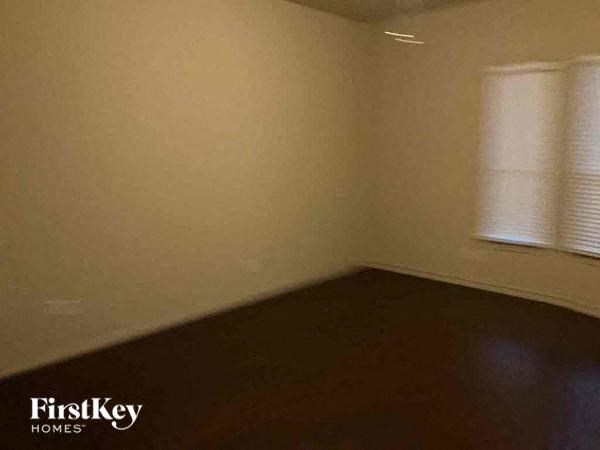 A room with a window covered by white blinds.