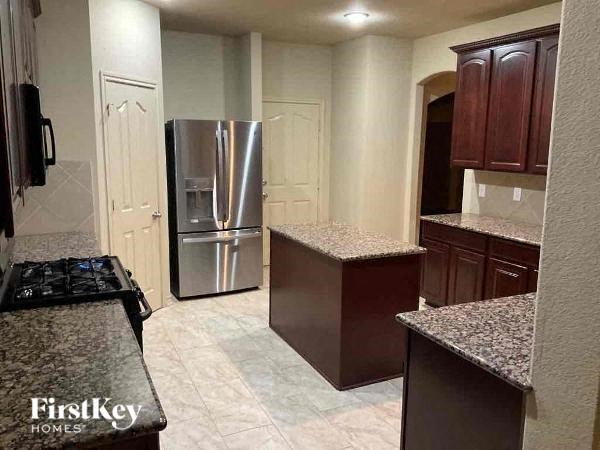 A kitchen with a granite countertop and a stainless steel refrigerator.