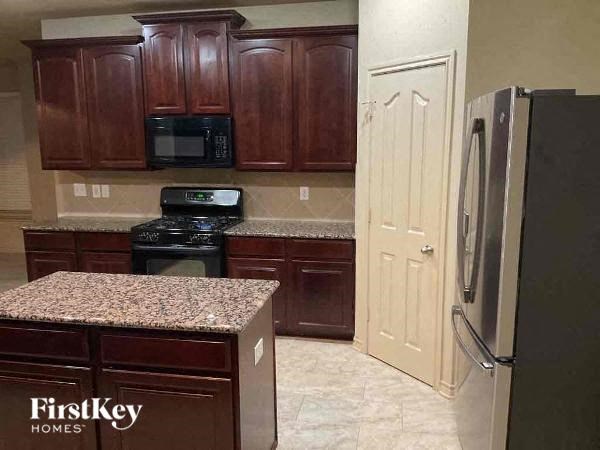 A kitchen with brown cabinets and a granite countertop.