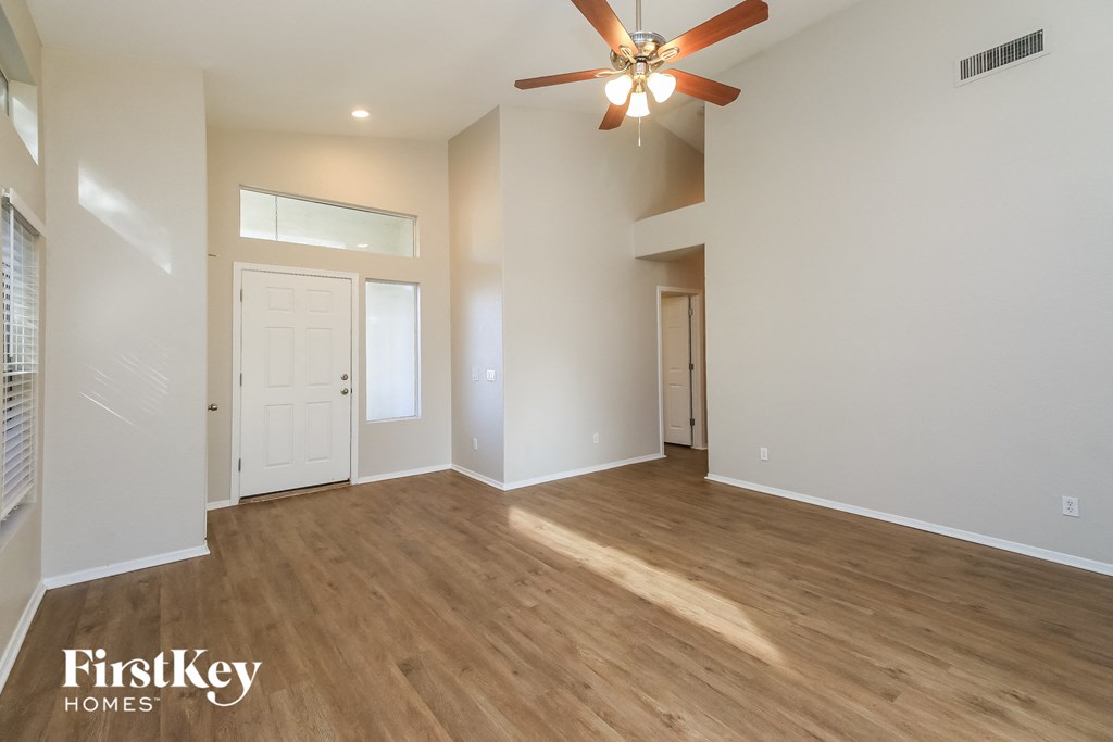 the living room and dining room of an empty house with a ceiling fan
