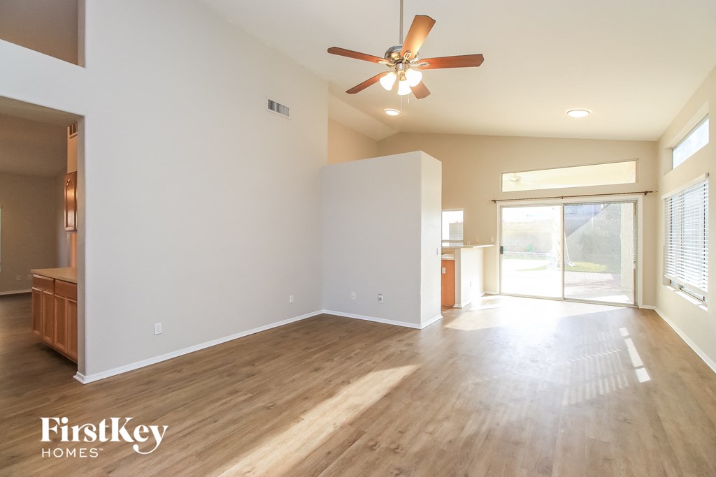 an empty living room with wood floors and a ceiling fan