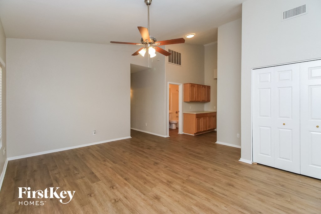 an empty living room with a ceiling fan and wood flooring