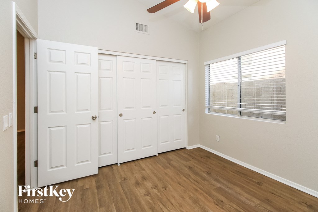 a bedroom with two closets and a window and a ceiling fan