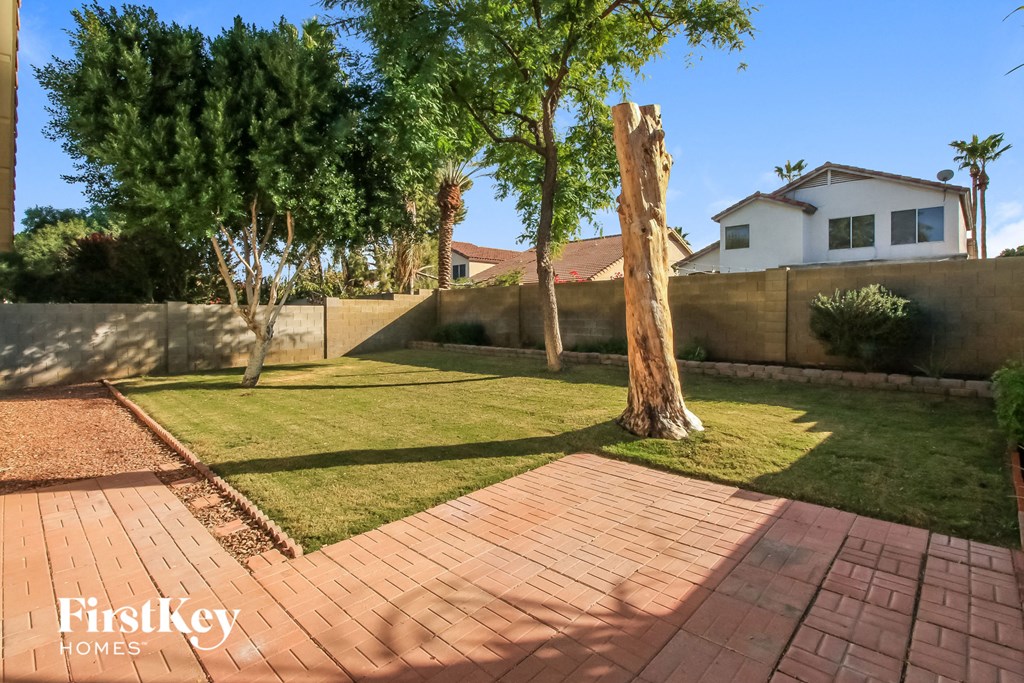 a backyard with grass and trees and a brick patio