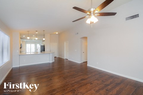 A spacious room with a ceiling fan and wooden flooring.