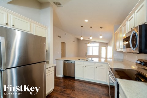 A modern kitchen with a stainless steel refrigerator and wooden floors.