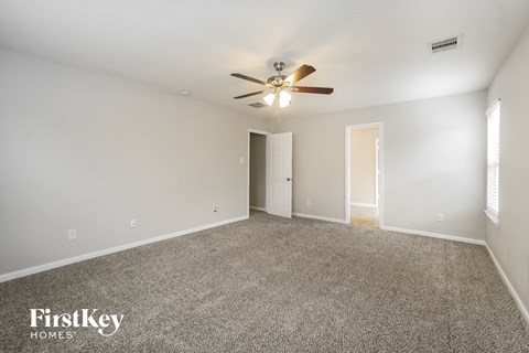 a spacious living room with carpet and a ceiling fan