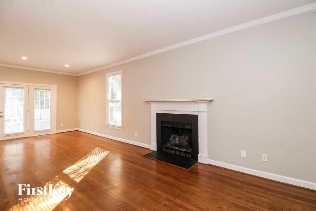 A large empty room with a fireplace and a window.