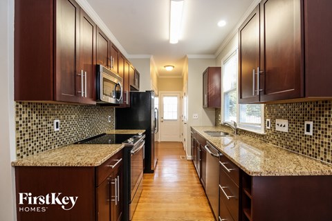 A kitchen with brown cabinets and a black fridge.