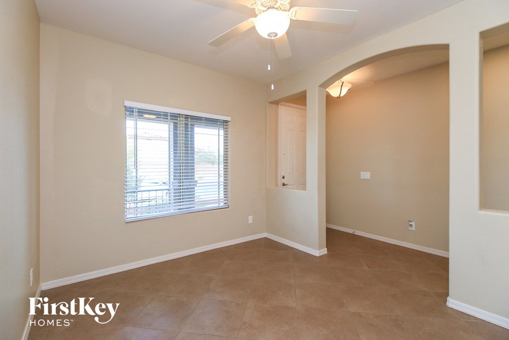 an empty living room with a ceiling fan and a window
