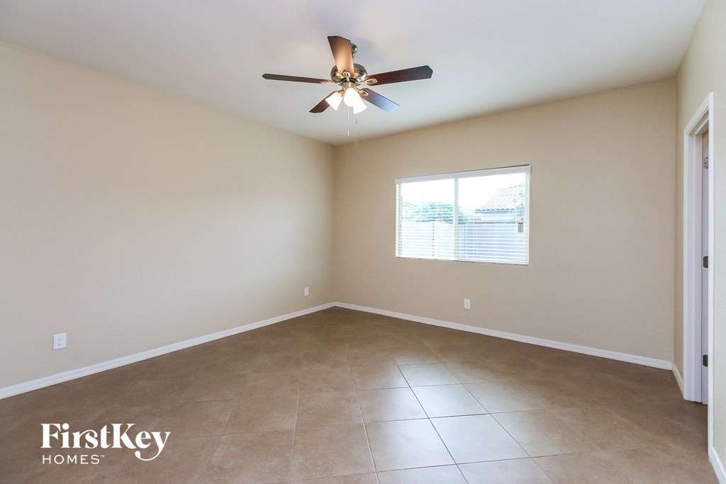 an empty living room with a ceiling fan and tiled floor
