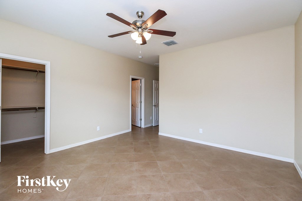 an empty living room with a ceiling fan and a closet