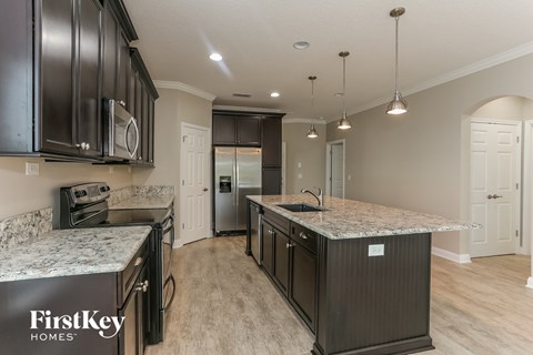 A kitchen with a marble countertop and black cabinets.