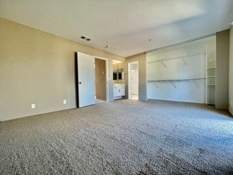 A spacious room with a carpeted floor and a staircase on the right side.
