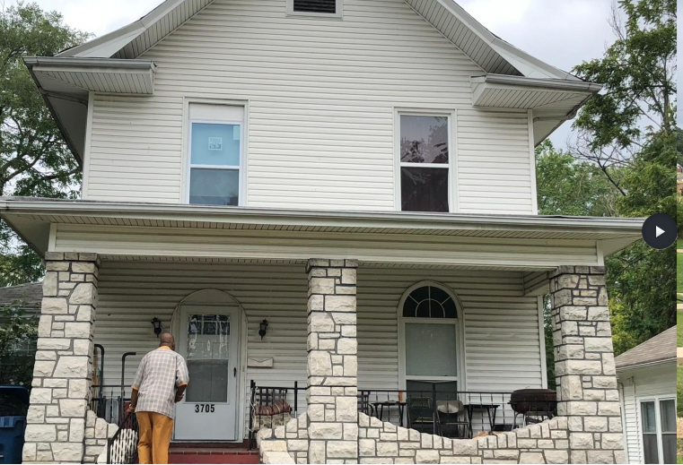 a man standing on the front porch of a white house