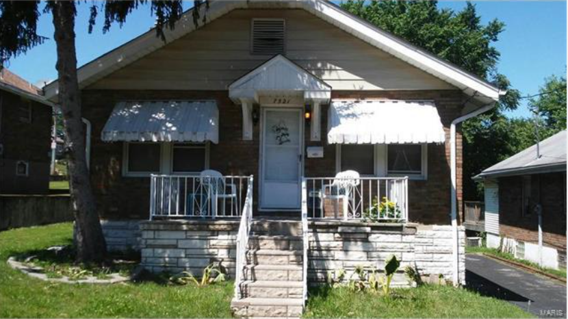 a small house with a white porch and a tree