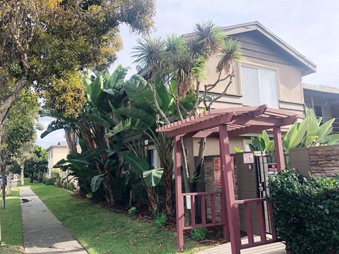 A house with a red wooden porch and a tree in front.