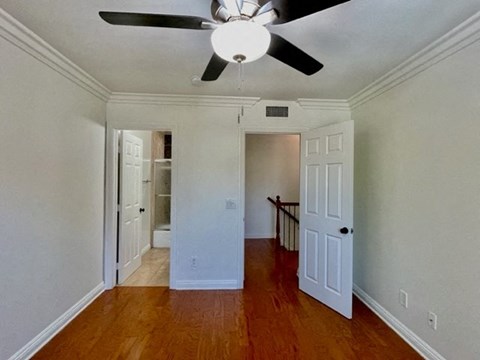 A room with a ceiling fan and wooden floors.