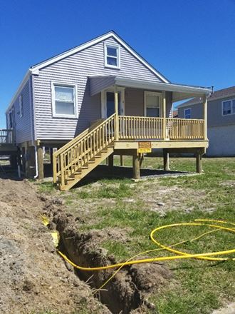 a house with a wooden deck and a hose on the ground