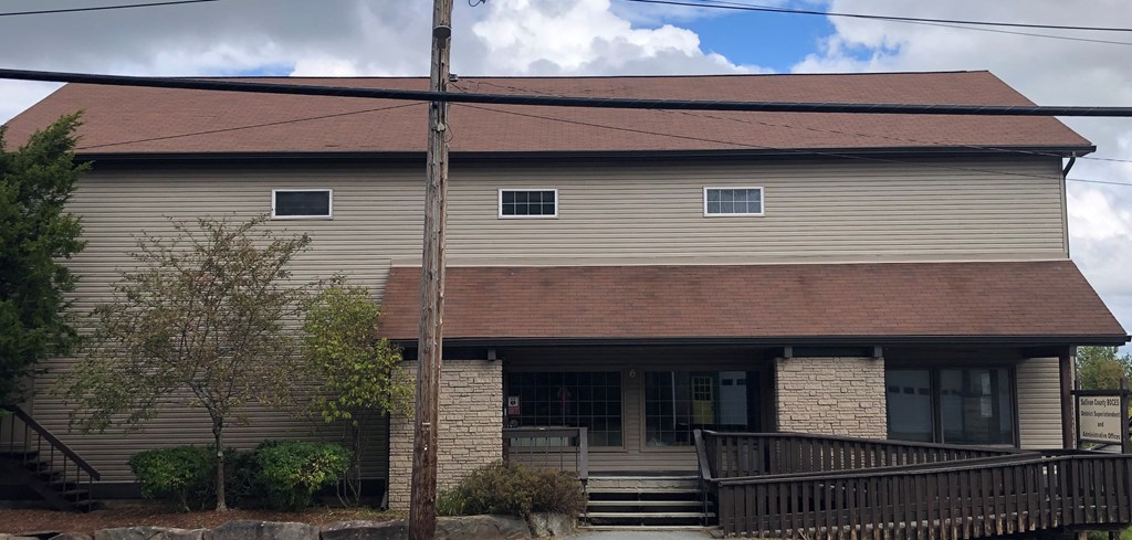 the front of a house with a brown roof and a wooden deck