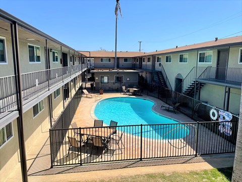 A black fence surrounds a small pool in a courtyard.