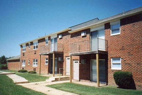 a brick apartment building with a balcony and a yard