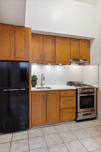 a kitchen with wooden cabinets and a black refrigerator