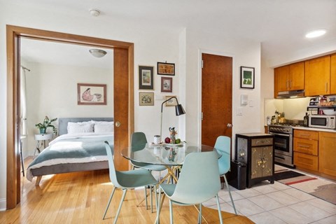 a bedroom with a bed and a dining room with a table and chairs