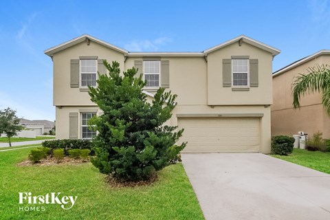 A house with a garage and a tree in front of it.