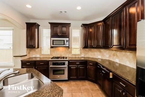 A kitchen with brown cabinets and a stove top oven.