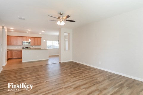 an empty living room and kitchen with a ceiling fan