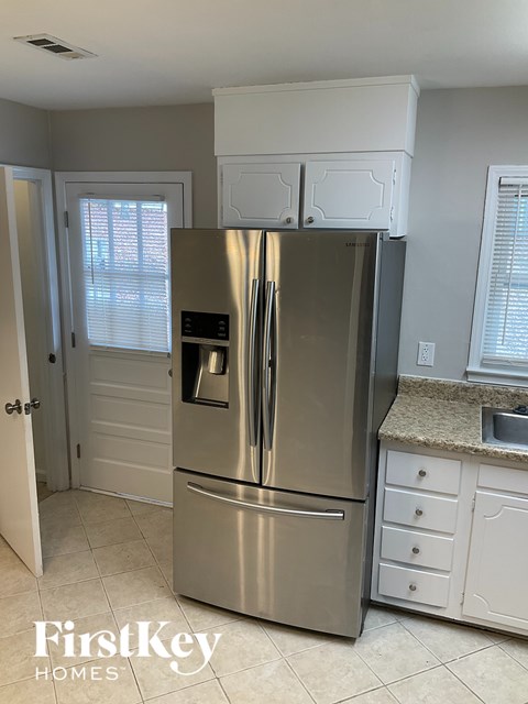 A stainless steel refrigerator in a kitchen with a FirstKey Homes logo.