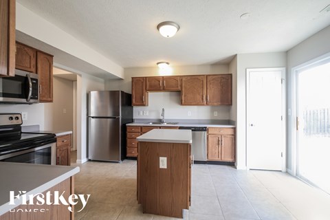 A kitchen with wooden cabinets and a stainless steel refrigerator.