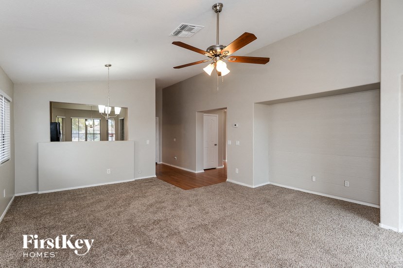 A spacious room with a ceiling fan and carpeted floor.
