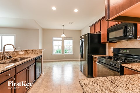 A kitchen with a black fridge and stove top oven.