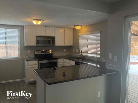 A kitchen with a black counter top and white cabinets.