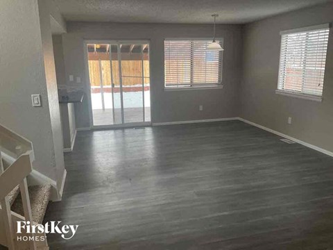 A spacious room with wooden flooring and a sliding glass door.