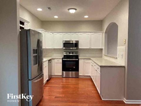 A kitchen with white cabinets and a wooden floor.