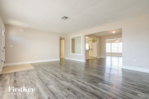 the living room and dining room of an empty house with wood flooring