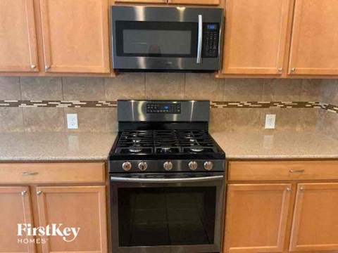 A kitchen with a stove top oven and microwave above it.