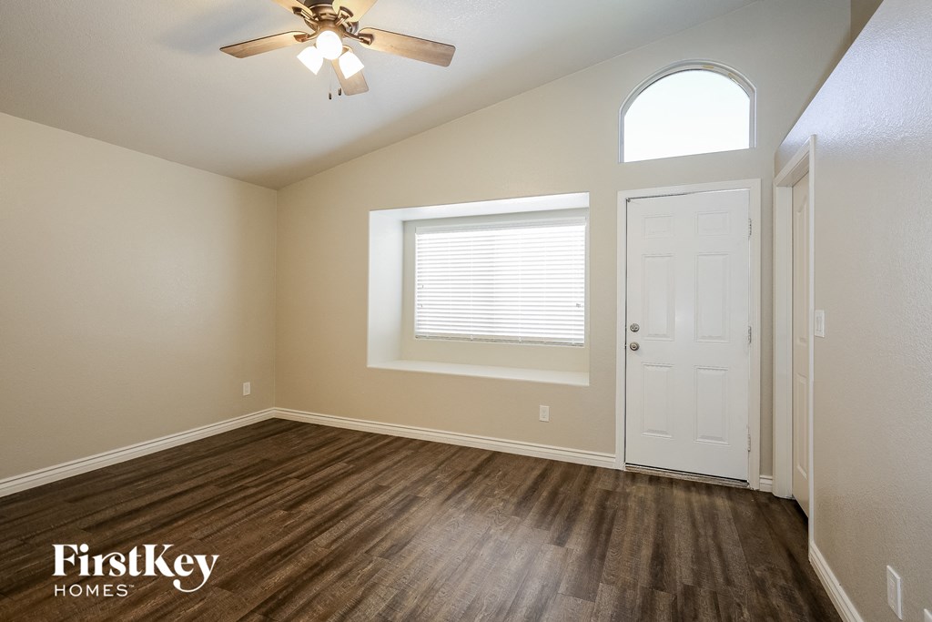 the spacious living room with hardwood floors and a ceiling fan