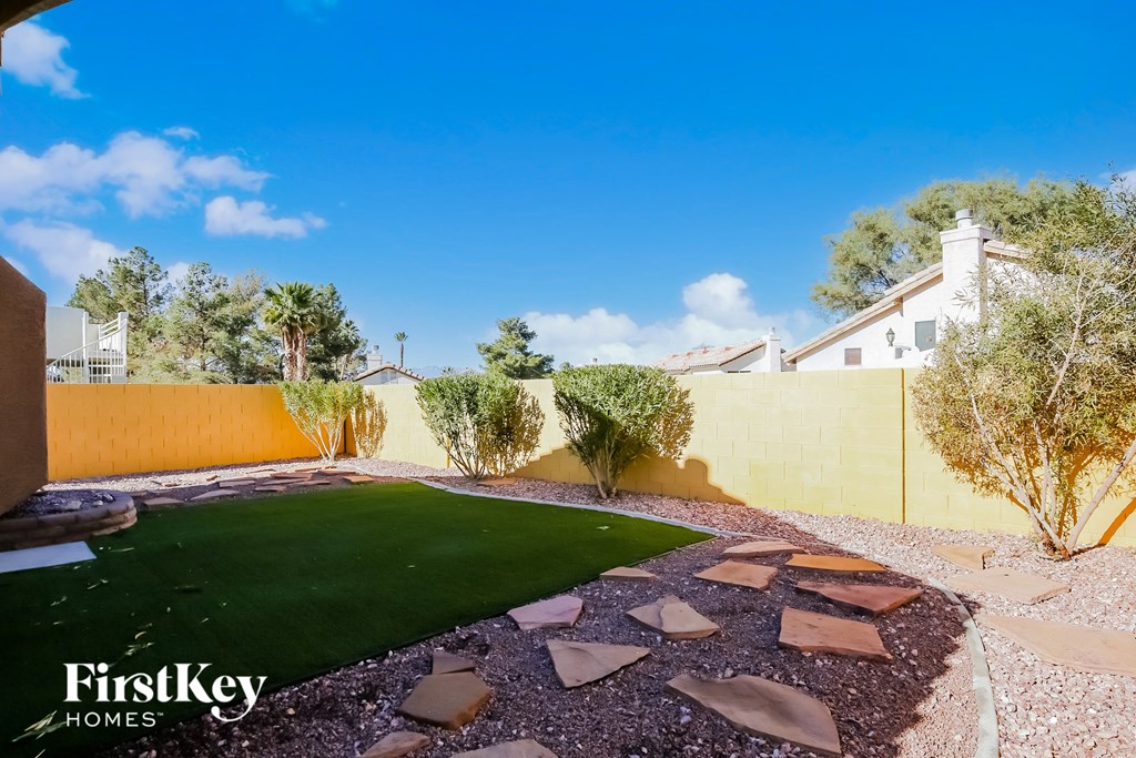 a backyard with artificial turf and a yellow fence