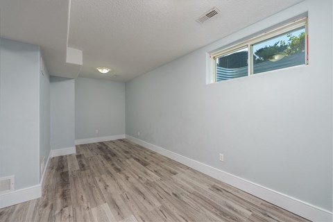 an empty living room with wood floors and a window