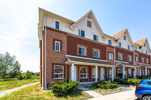 a brick apartment building with a blue car parked in front